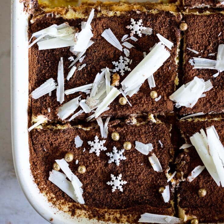 Chocolate tiramisu dessert with white chocolate shavings, snowflake sprinkles, and edible gold beads, perfect for holiday or special occasion celebrations.