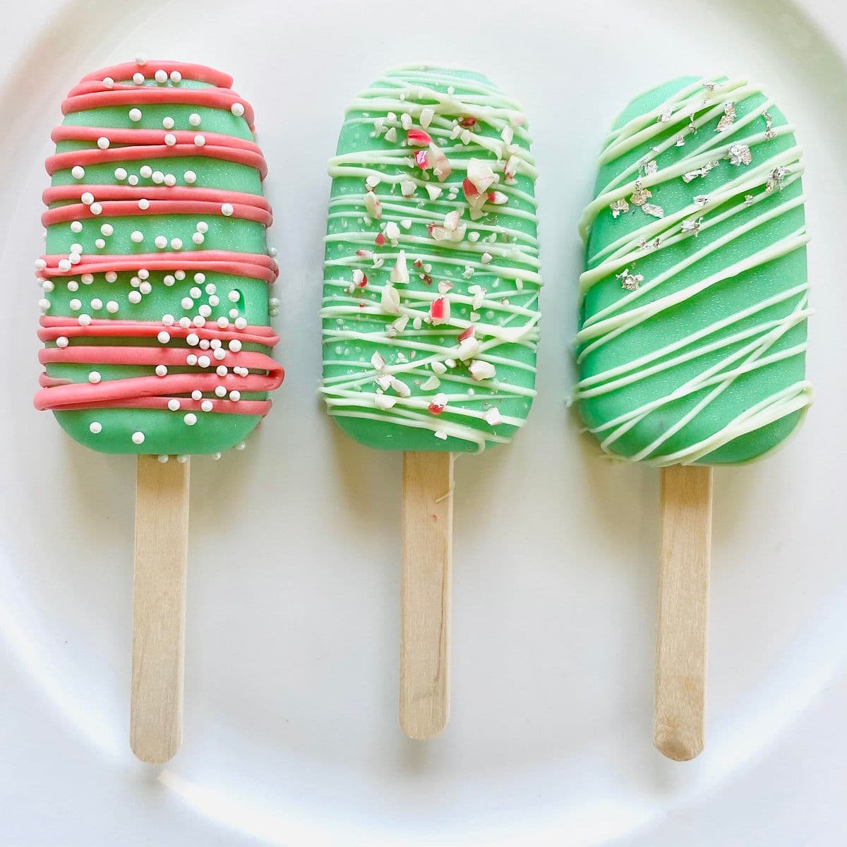 Colorful holiday-themed popsicle desserts decorated with white, red, and silver sprinkles, ideal for festive occasions and special treats.