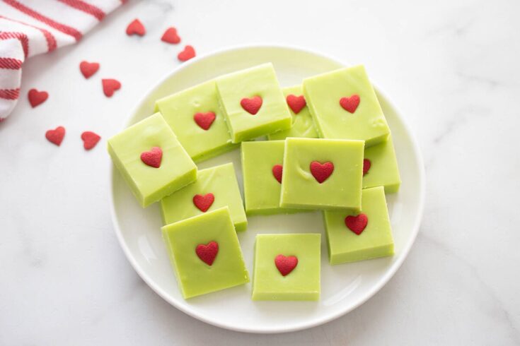 Bright green matcha white chocolate fudge squares decorated with small red heart toppers on a white plate, perfect for Valentine's Day or romantic gifts.