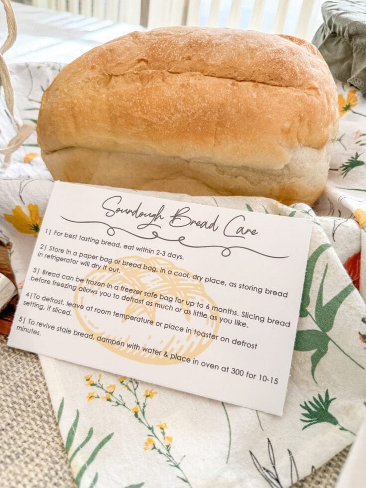 Fresh homemade sourdough bread on a floral cloth with baking instructions visible.