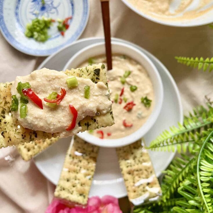Creamy vegan spinach artichoke dip served with crisp crackers and fresh herbs, ideal for sharing and entertaining. Perfect for dips, appetizer parties, or snacking with friends and family.