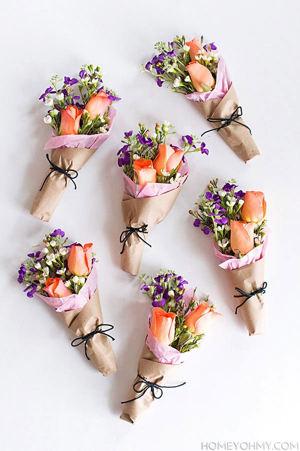 Delicate floral arrangements in paper wraps with peach roses and purple blooms, ideal for gift or wedding decor, from A Hundred Affections.