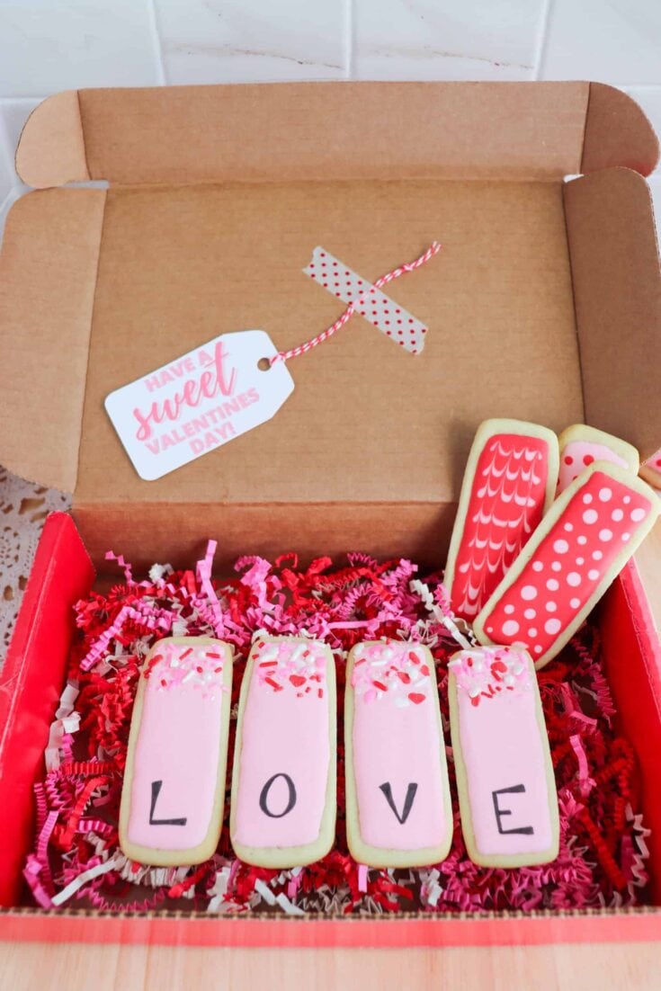 Sweet Valentine's cookies spelling "LOVE" in a gift box with pink and red decorations, perfect for expressing love and affection on Valentine's Day.