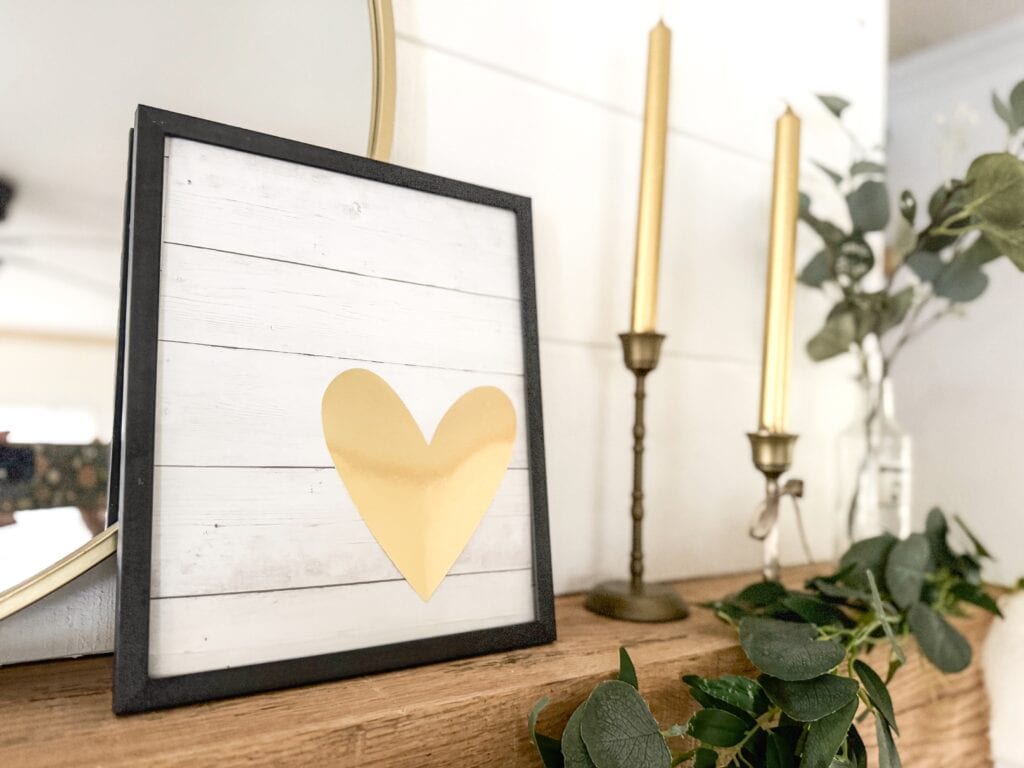 gold heart in valentine wall art with gold candles on mantel