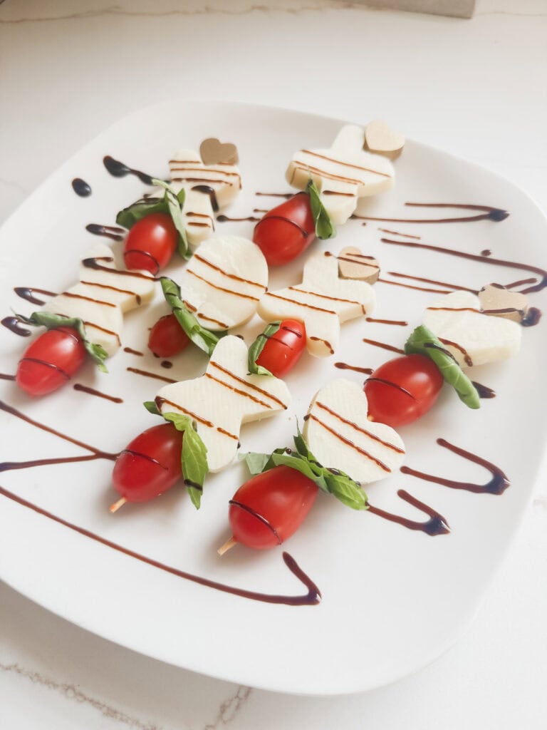 xo valentine mozzarelle tomato caprese kabobs on a skewer on plate with balsamic vinegar glaze