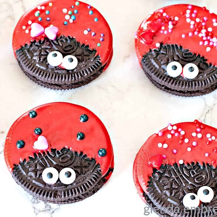 Bright red and chocolate cookies decorated to look like ladybugs with googly eye candies and colorful sprinkles for a cute, playful dessert perfect for Valentine's Day or kids' parties.