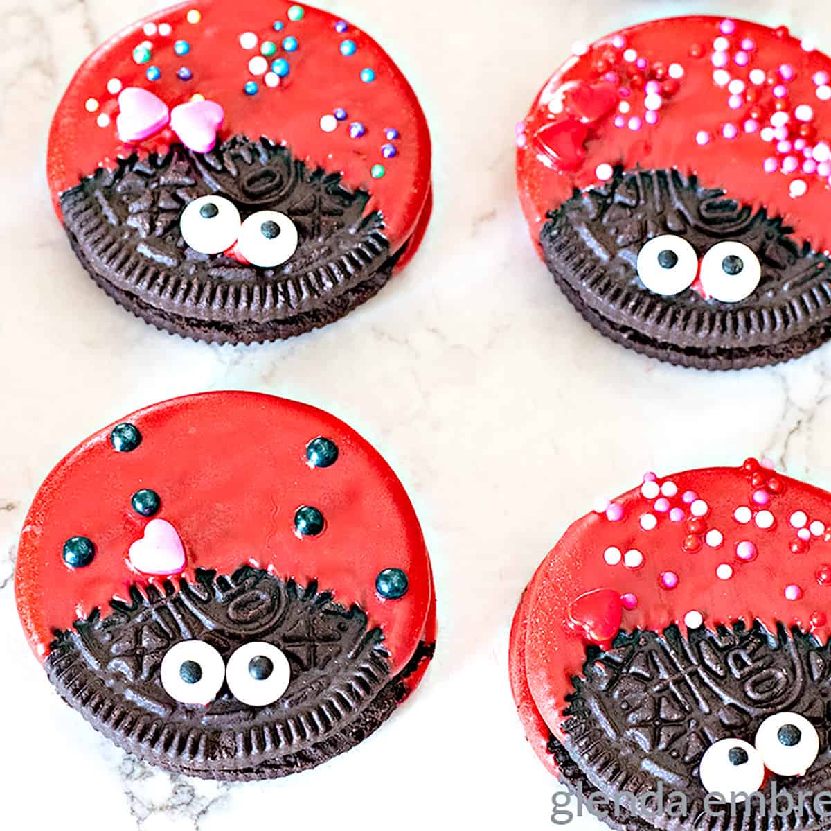 Bright red and chocolate cookies decorated to look like ladybugs with googly eye candies and colorful sprinkles for a cute, playful dessert perfect for Valentine's Day or kids' parties.