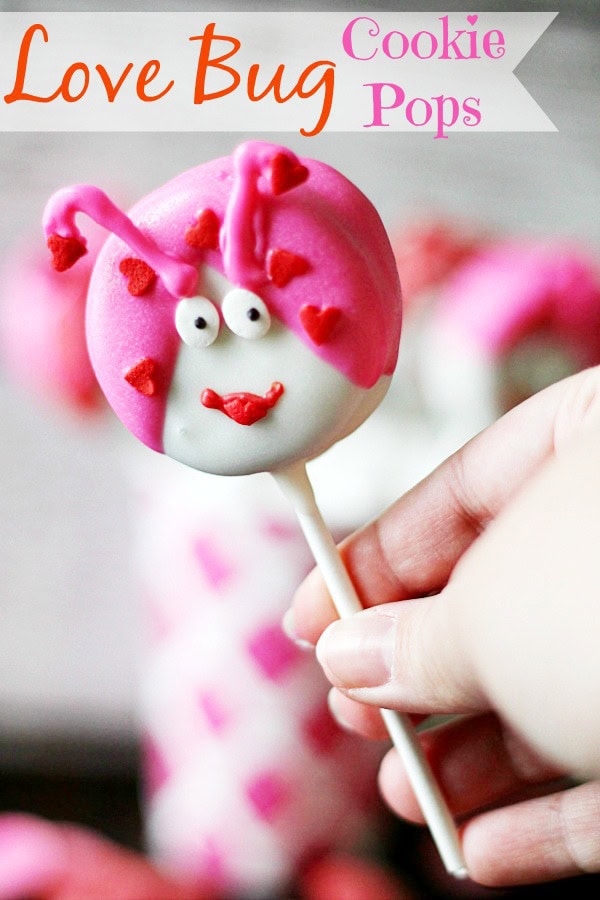 Love Bug Cookie Pops with cute face and pink heart decorations, perfect for Valentine's Day or special treats. Handheld dessert on a stick, vibrant pink and white colors.
