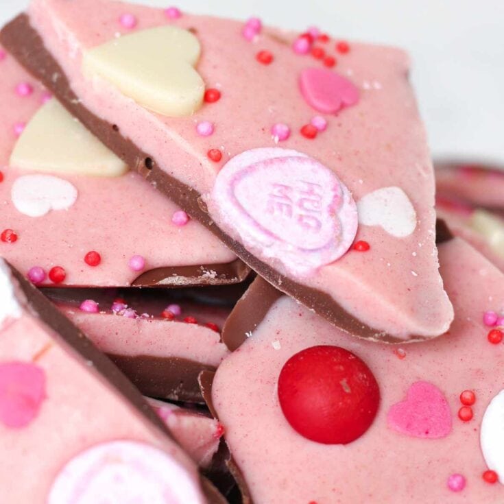 Pink Valentine’s Day heart-shaped cookies with white and pink chocolate decorations, red and pink sprinkles, and colorful candy accents, perfect for romantic celebrations or sweet gifts, from A Hundred Affections.