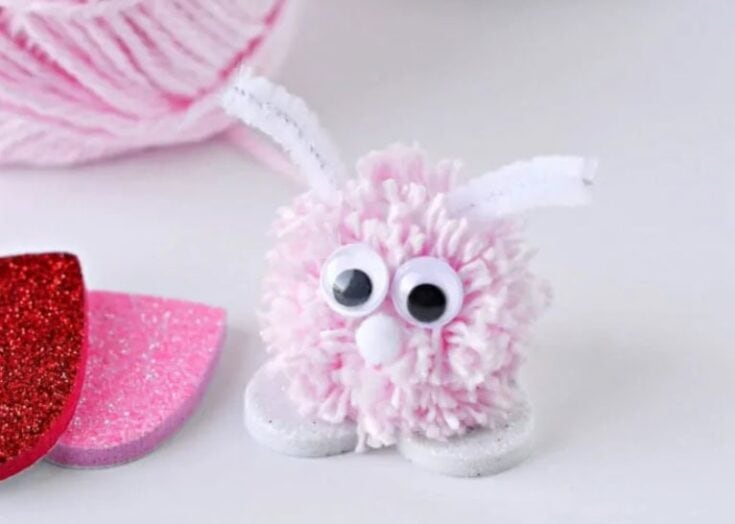 Pink fluffy bunny craft with googly eyes, yarn ears, and surrounded by colorful foam hearts, perfect for adorable handmade gift ideas and craft projects from A Hundred Affections.