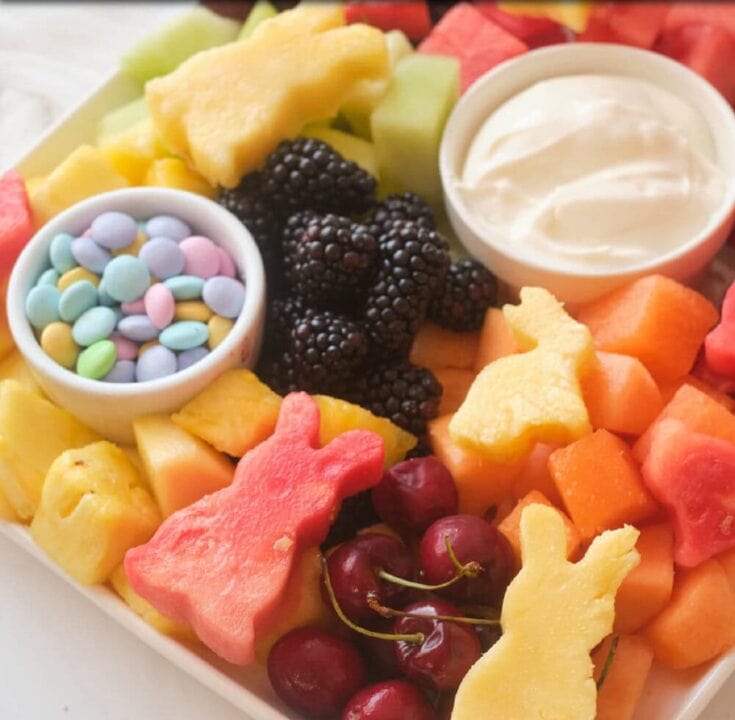 Colorful fruit platter with pineapple, watermelon, cherries, blackberries, and melon, served with sweet cream and pastel candy sprinkles, perfect for a healthy, vibrant snack or dessert.
