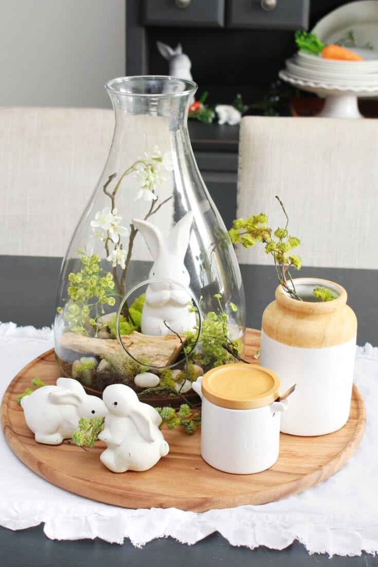 Whimsical Easter-themed decor with ceramic bunny figurines, glass jar centerpiece, and rustic wooden accents for spring holiday celebration.