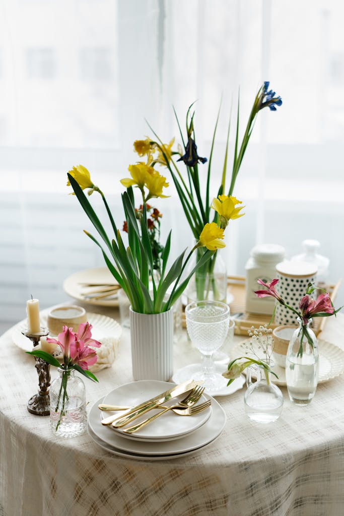 A beautifully arranged dining table with daffodils and elegant tableware, perfect for a spring gathering.