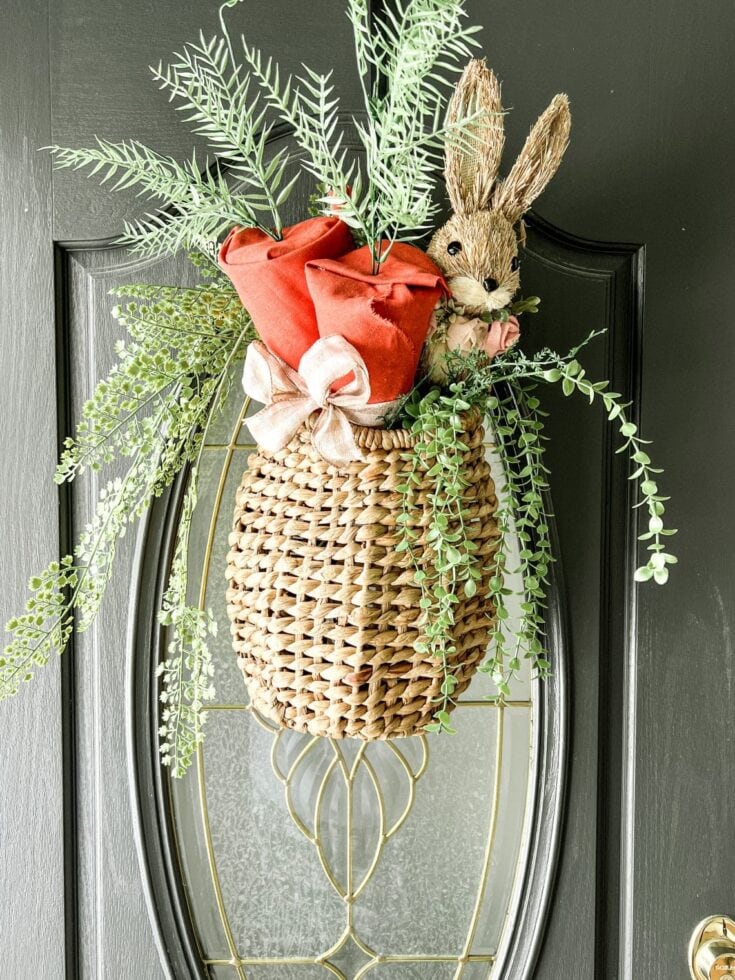 Soft woven basket floral arrangement with greenery, a plush bunny, and a red fabric flower decoration, perfect for Easter or spring decor.