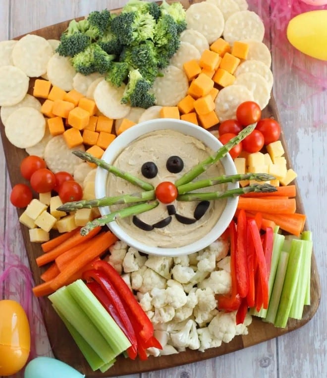 Fresh vegetable platter with cheese, cherry tomatoes, and dip decorated as a cute cat face, perfect for healthy snacking and festive occasions.