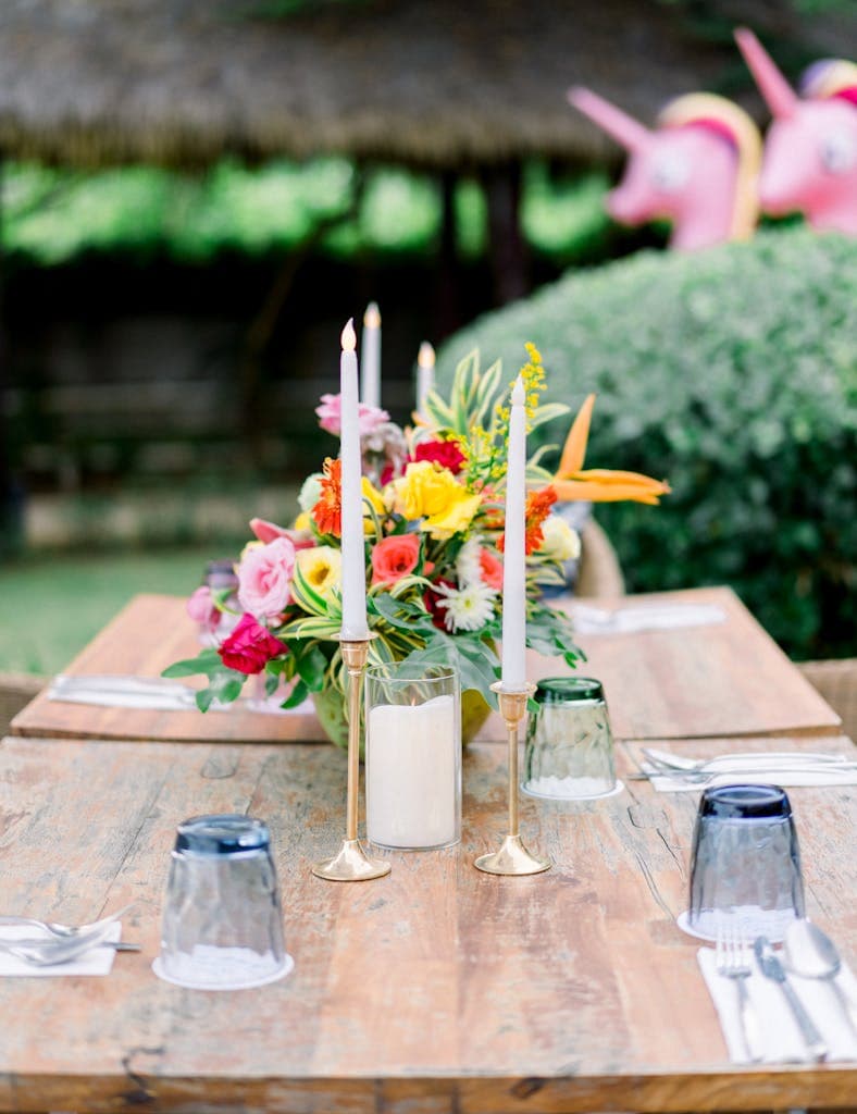 Charming outdoor table setup featuring vibrant floral arrangement and candles, perfect for alfresco dining.