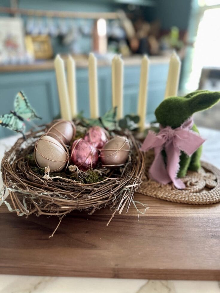 Eggs in a nest with butterfly decorations, pink flowers, and candles, styled for spring or Easter celebrations, emphasizing beauty, craftsmanship, and seasonal decor.