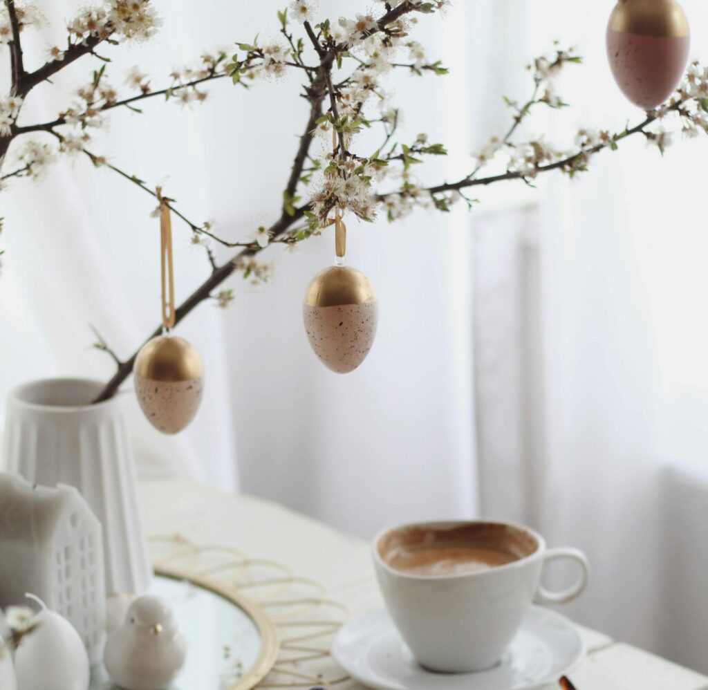 Decorative Easter egg ornaments hanging on blossoming branch for spring holiday celebration.