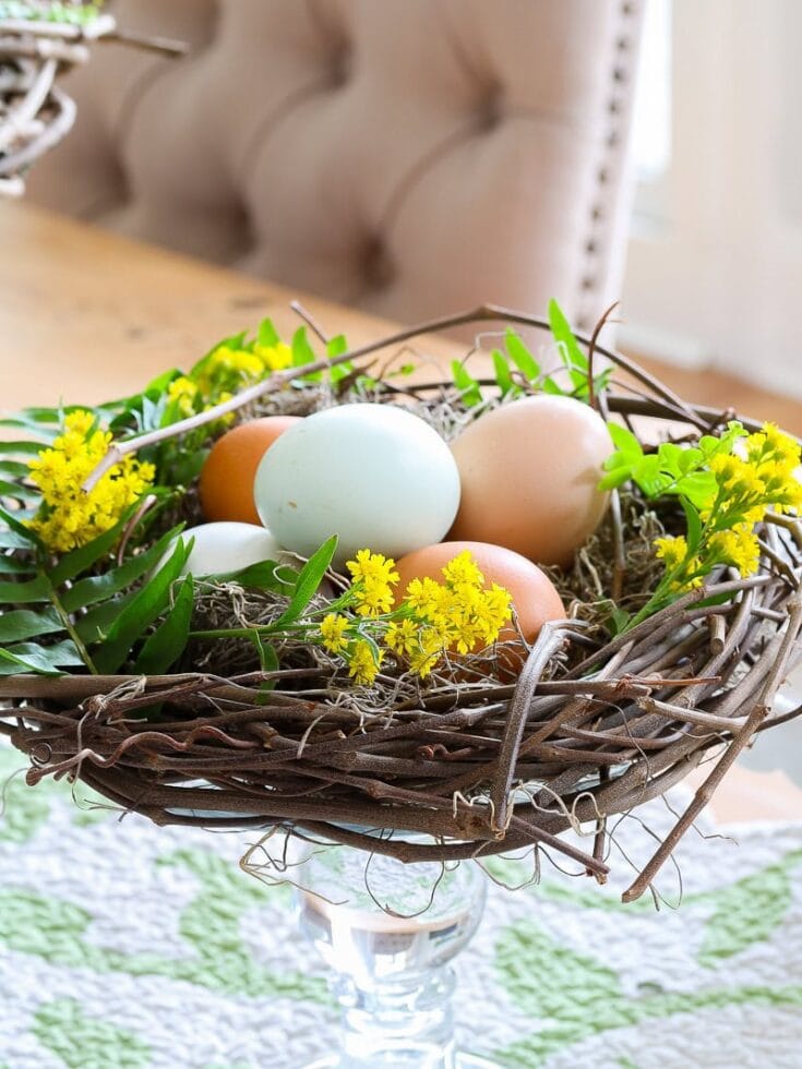 Colorful Easter eggs in a decorative nest with yellow flowers and green foliage. Perfect for spring holiday decorations and festive Easter celebrations.