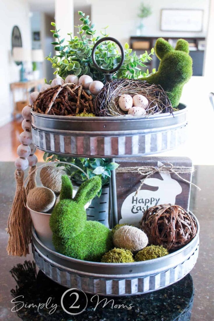 Delightful Easter centerpiece with greenery moss and decorated eggs on galvanized tiered tray.