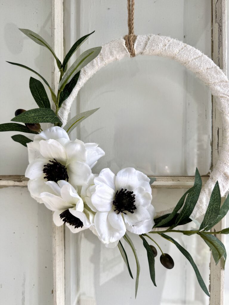 Soft white flowers with dark centers and green foliage on a rustic white wooden background, perfect for elegant floral decor and wedding arrangements.
