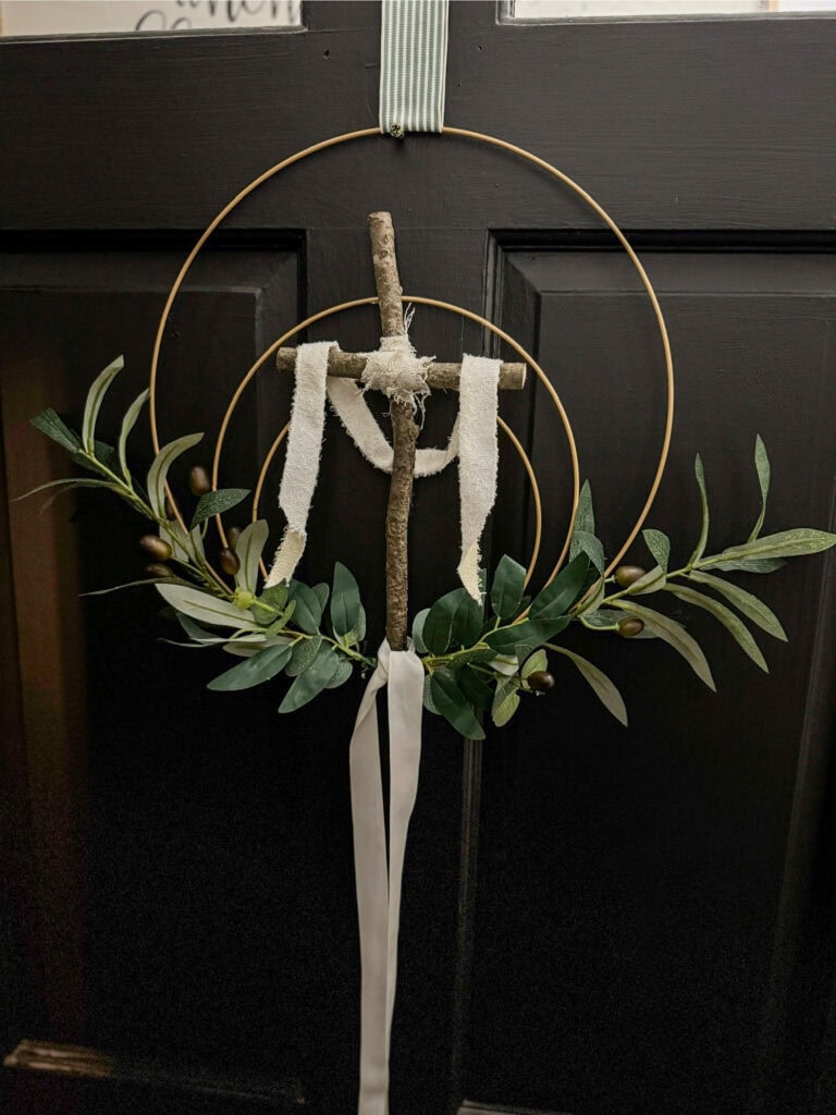 Wreath wall hanging with wooden cross, greenery, and ribbon, ideal for rustic, boho, or farmhouse decor, perfect for spring or Easter celebrations.