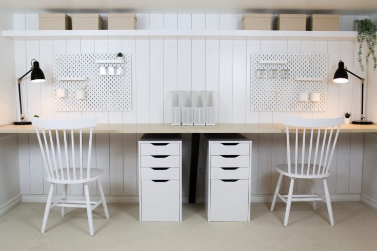 Bright modern home office workspace with white desks, desk organizers, black task lamps, and white chairs; stylish minimalist decor ideal for productivity.