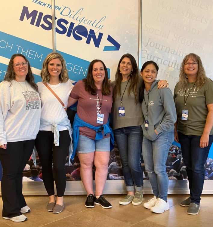 Teaching and empowerment workshop attendees at A Hundred Affections conference in front of inspirational mission and education signage.