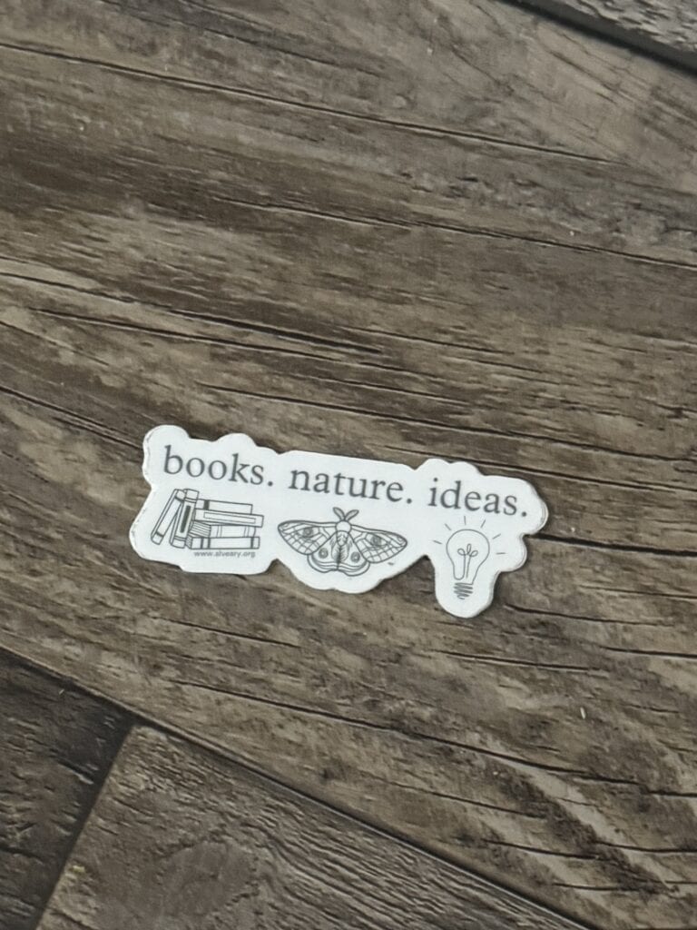 Books. nature. ideas. sticker featuring books, a moth, and a light bulb on rustic wooden surface.