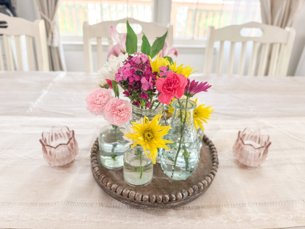summer centerpiece with fresh blooms with pink glass votives on the side