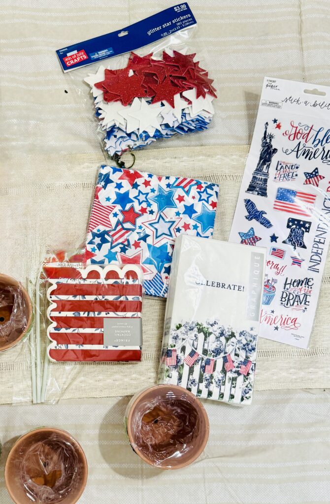 Festive 4th of July craft supplies including star-shaped glitter stickers, patriotic patterned napkins, American flag-themed paper towels, and cupcake toppers, perfect for holiday decorating.
