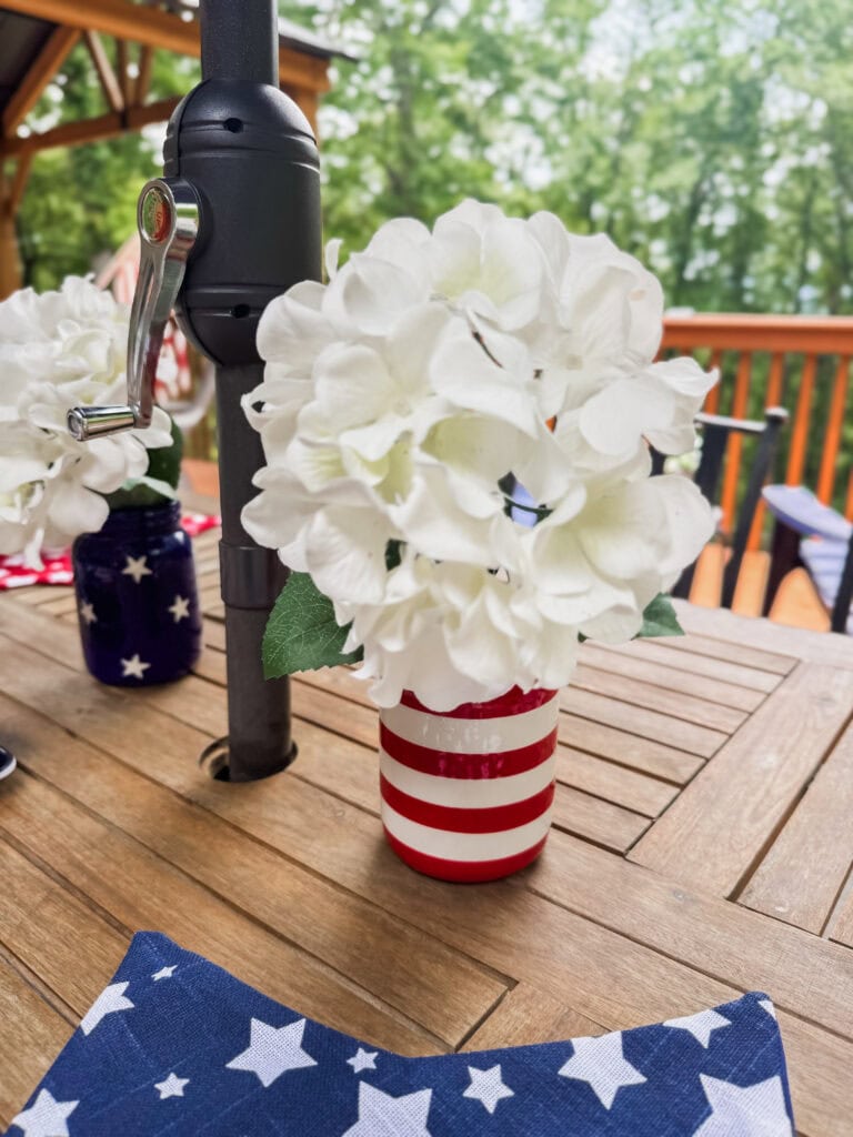 red and white striped mason jar vase with hydrangea on patriotic outdoor table