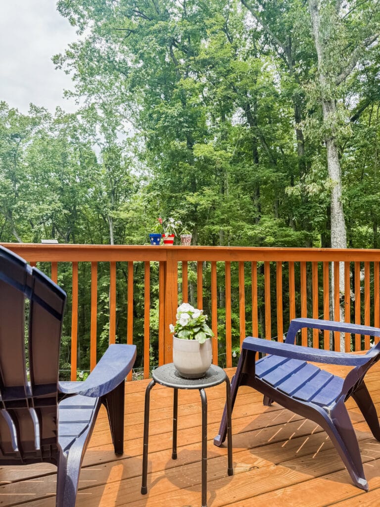 blue adirondack chairs with flowers in between on deck
