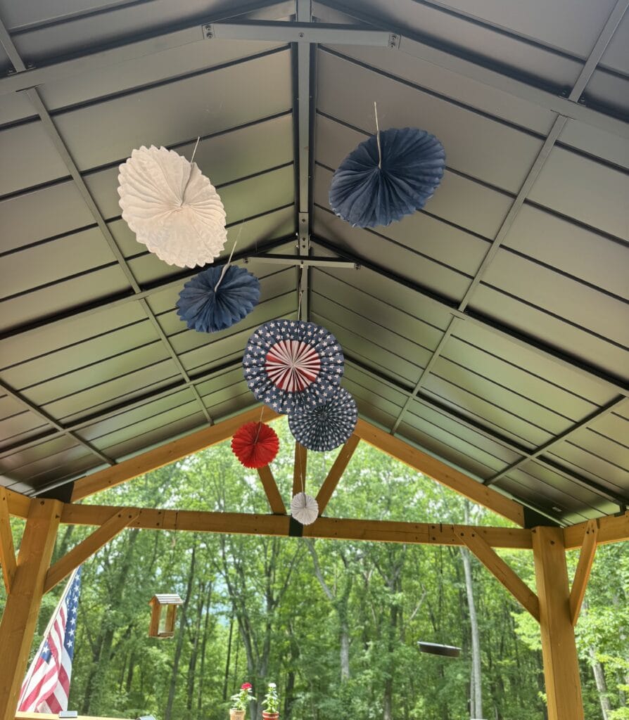 paper pinwheel rosettes hanging from top of gazebo for 4th of July decor 
