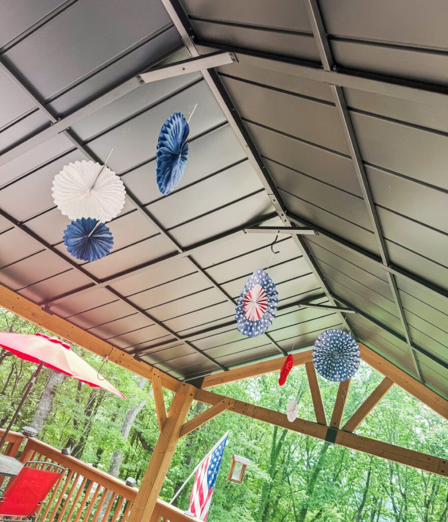 paper pinwheel rosettes hanging from top of gazebo for 4th of July decor 
