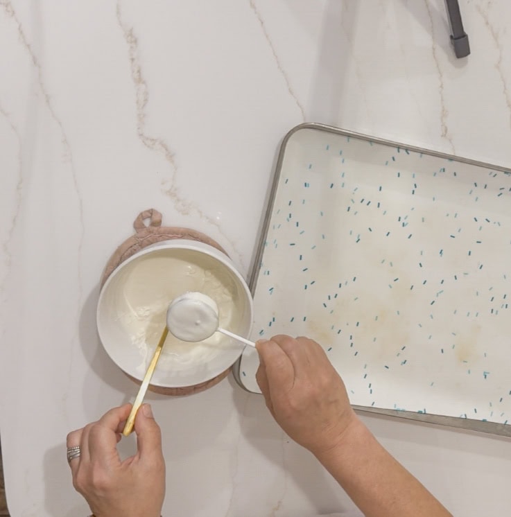 Frozen dessert making process, ice cream being scooped into a bowl, minimalistic background, home kitchen setting, dessert preparation at A Hundred Affections.