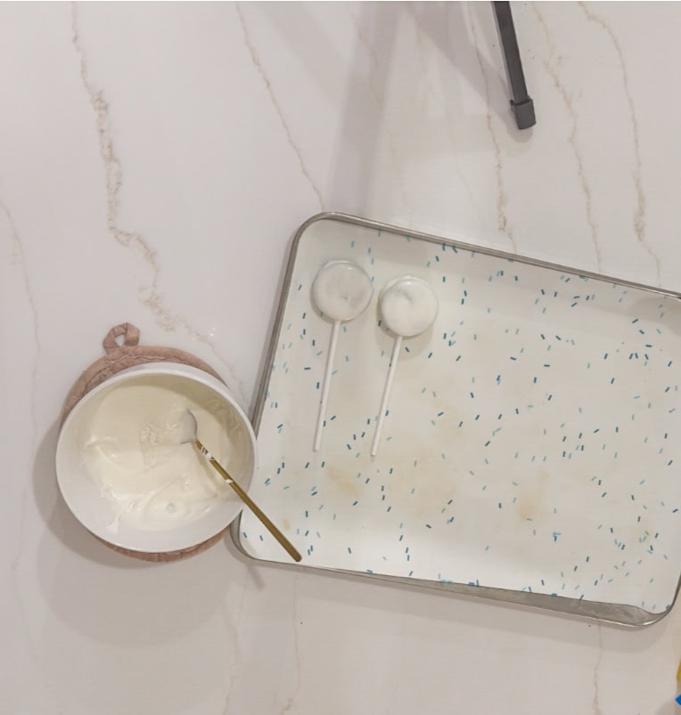 Cream cheese on a spoon with two lollipops on a decorated tray, ready for dessert or snacks at A Hundred Affections.