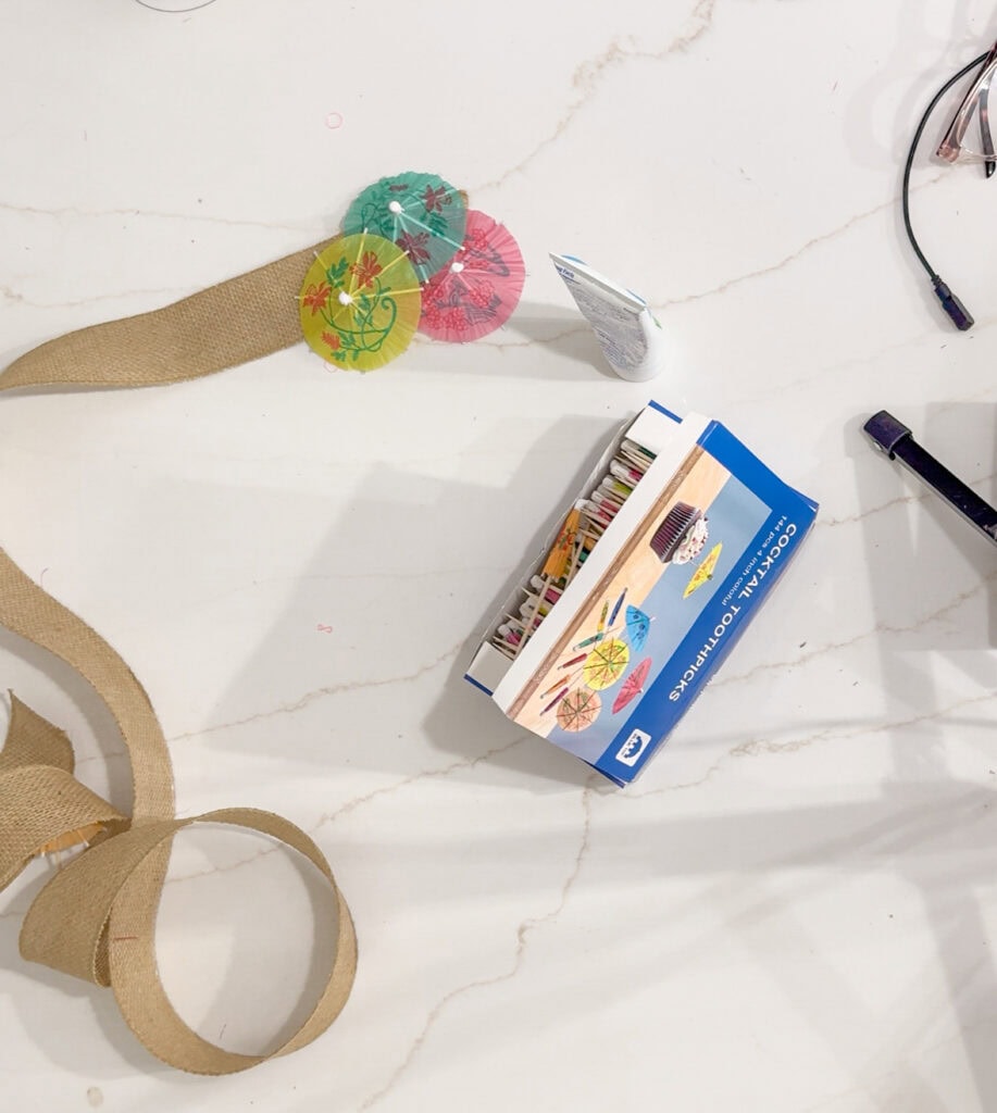 Colorful paper parasols craft kit on white marble countertop, showcasing DIY summer decoration supplies from A Hundred Affections.