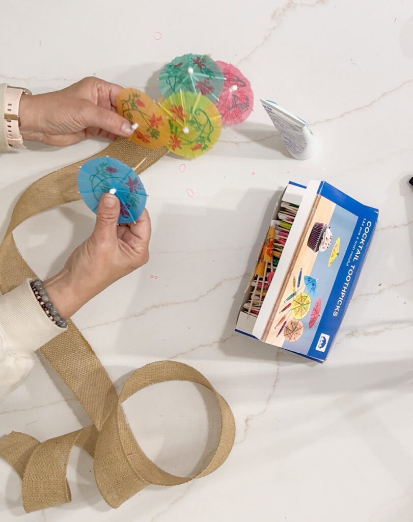 Colorful paper cocktail umbrellas for craft or party decoration on a white marble surface.