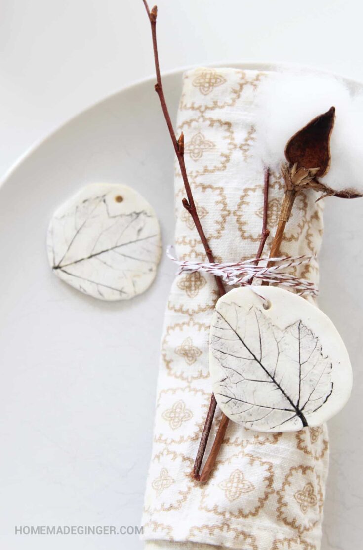 Delicate autumn-themed decor with dried leaves and cotton stems on a cozy cloth napkin for fall table settings.
