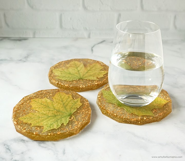 Vegan resin coasters with realistic green maple leaf designs on a white marble surface, featuring a clear glass of water on one coaster, perfect for home decor and protecting surfaces.