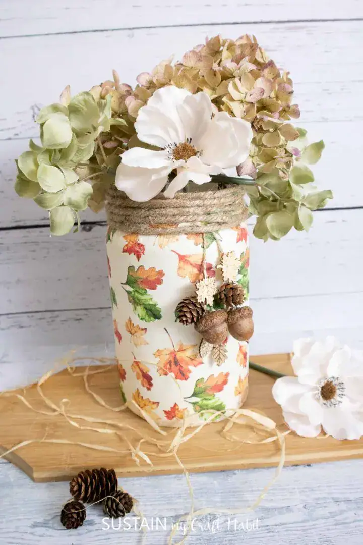 Vase with Fall Leaves and Hydrangeas, rustic autumn floral arrangement in decorated jar, cozy fall decor for home or Thanksgiving, natural and handmade flower centerpiece, seasonal craft display.
