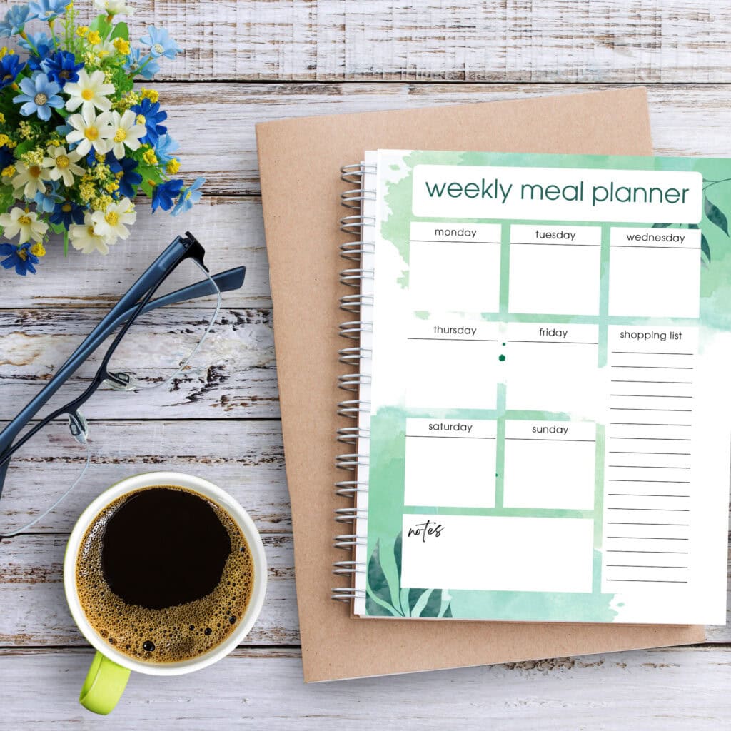Fresh weekly meal planner with leafy green accents, perfect for organizing your home cooking schedule. Ideal for a healthy lifestyle and meal prep on a clean, rustic desk.