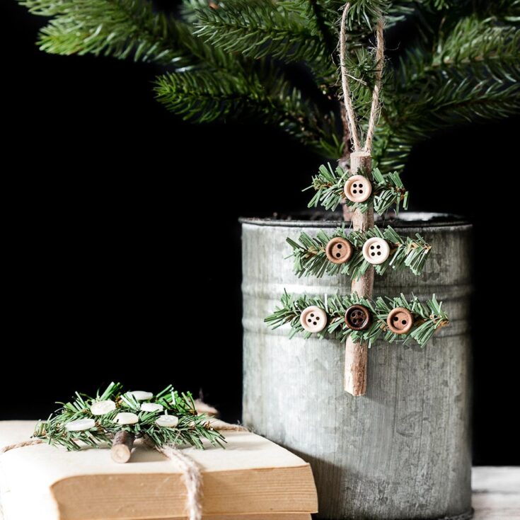 Button-embellished miniature Christmas tree DIY decor made with natural twigs, greenery, and small buttons, perfect for rustic holiday decoration and craft projects.