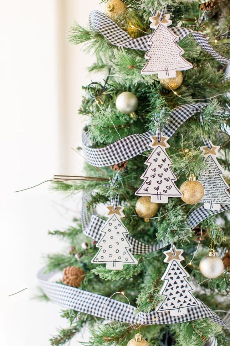 Brightly decorated Christmas tree with black and white checked ribbons, handmade paper tree ornaments, gold baubles, pinecones, and warm string lights for festive holiday decor.