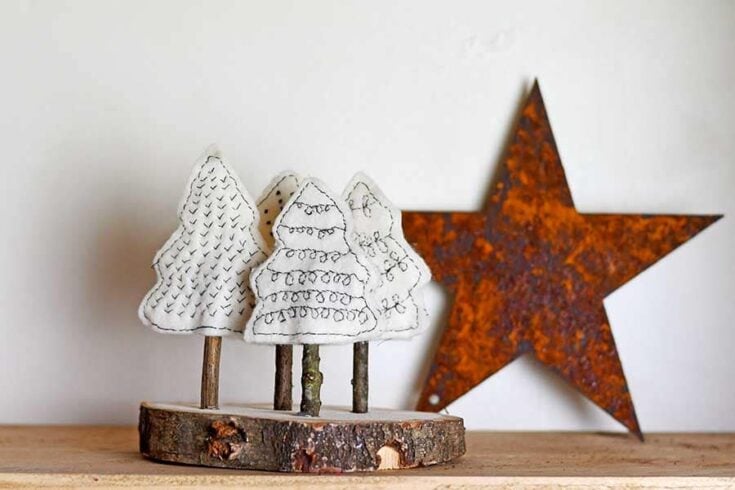 Whimsical handmade Christmas trees with embroidered fabric and rustic wood base, paired with a vintage rusty metal star, perfect for festive holiday decor and DIY holiday crafts.