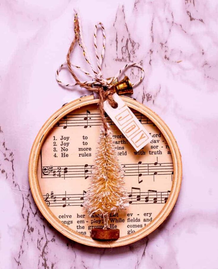 Joyful wooden embroidery hoop ornament with musical sheet design, twine bow, and decorative tags, perfect for home decor or gift embellishments.