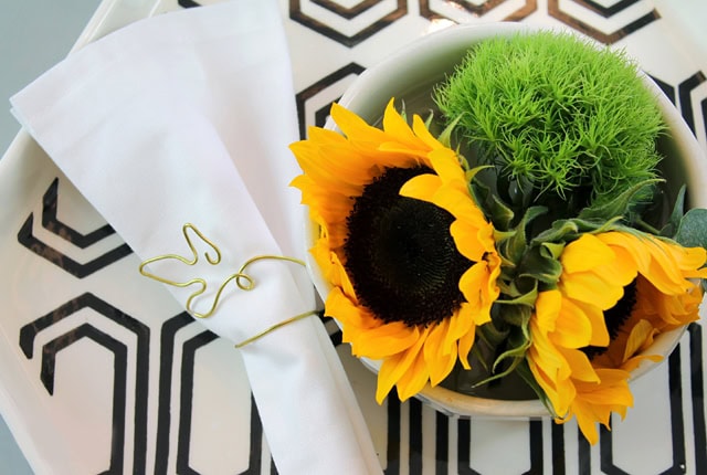 Bright sunflower bouquet with green moss in a white vase, stylishly arranged on a geometric table, perfect for summer decor and floral gifts.