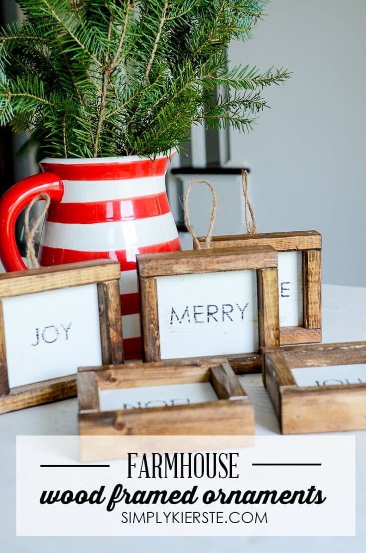 Bright red and white striped pitcher filled with green pine branches, next to rustic wooden framed ornaments with holiday words like "Joy" and "Merry," perfect for farmhouse holiday decor.