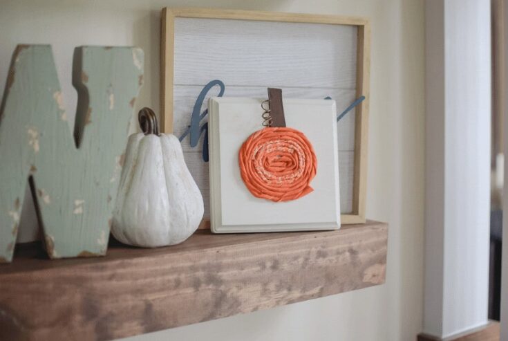 Rustic wooden shelf decorated with a white pumpkin and colorful fabric flower art, perfect for farmhouse home decor, craft displays, and cozy interior accents.